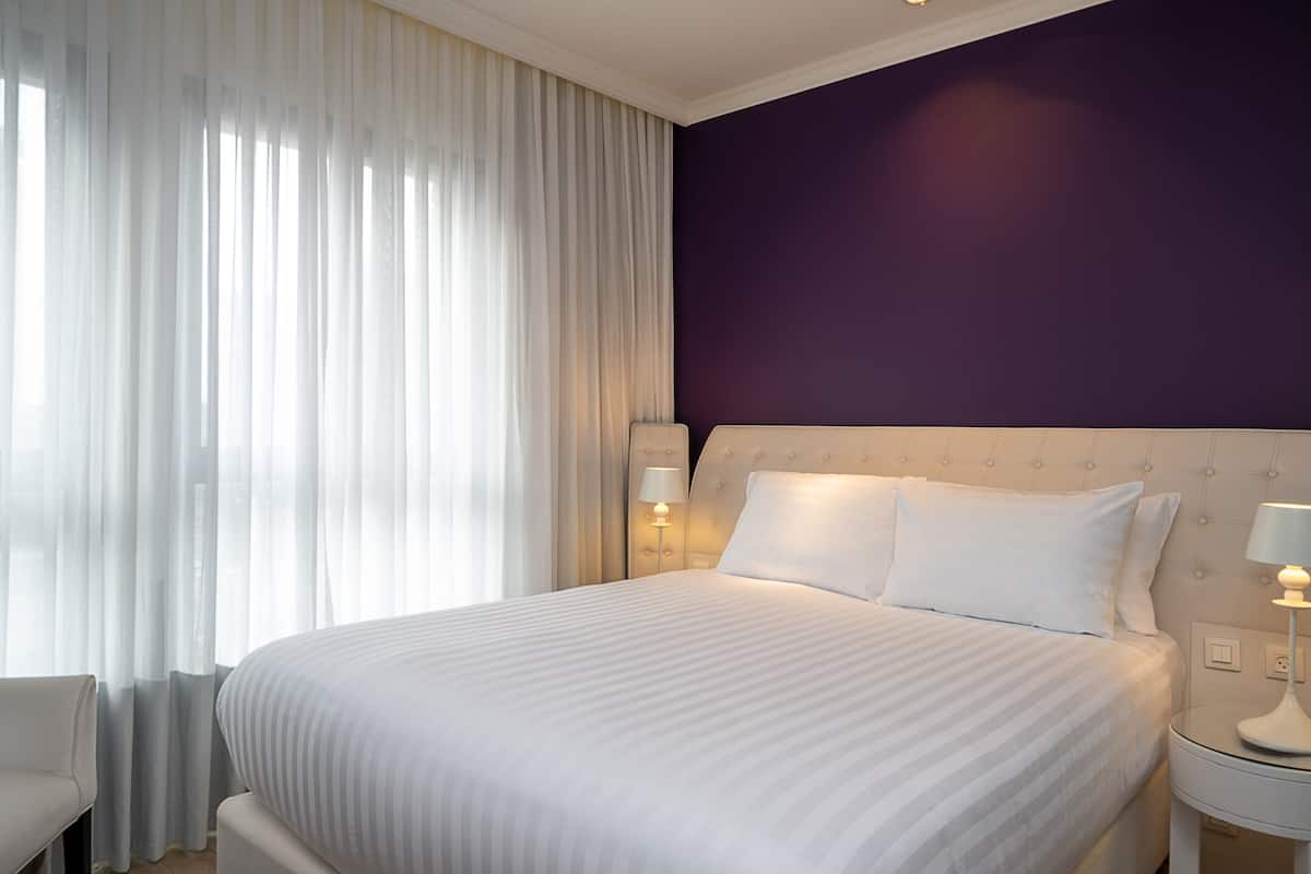 Een hotelkamer met een groot bed, een nachtkastje met een lamp en een stoel.