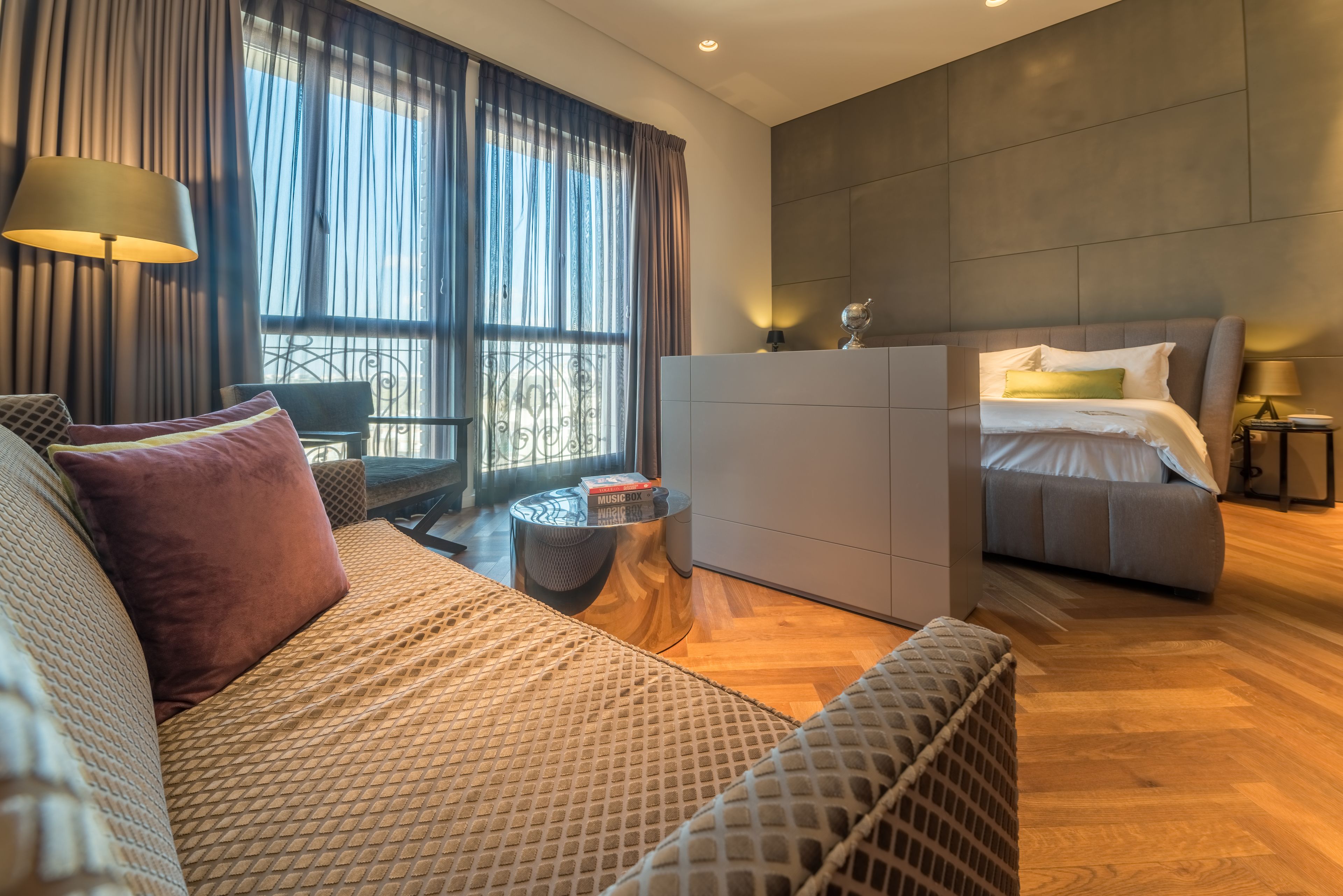 Una habitación de hotel moderna con una cama grande, un sofá, una mesita y un escritorio.