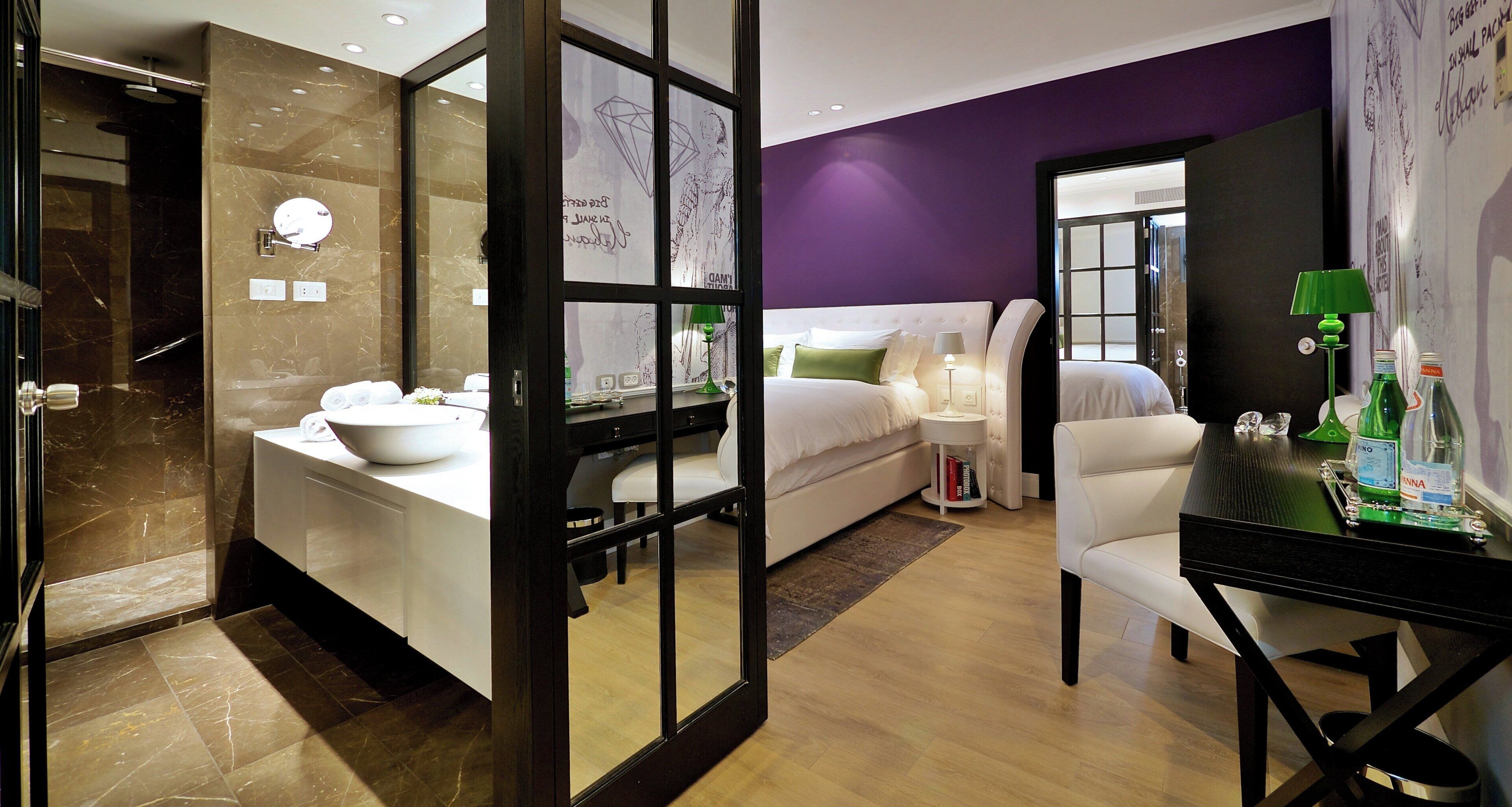Een moderne hotelkamer met een badkamer, een bed, een bureau en een stoel.