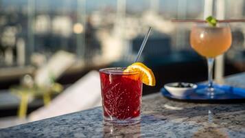 A glass of red beverage with an orange slice garnish on a marble surface.