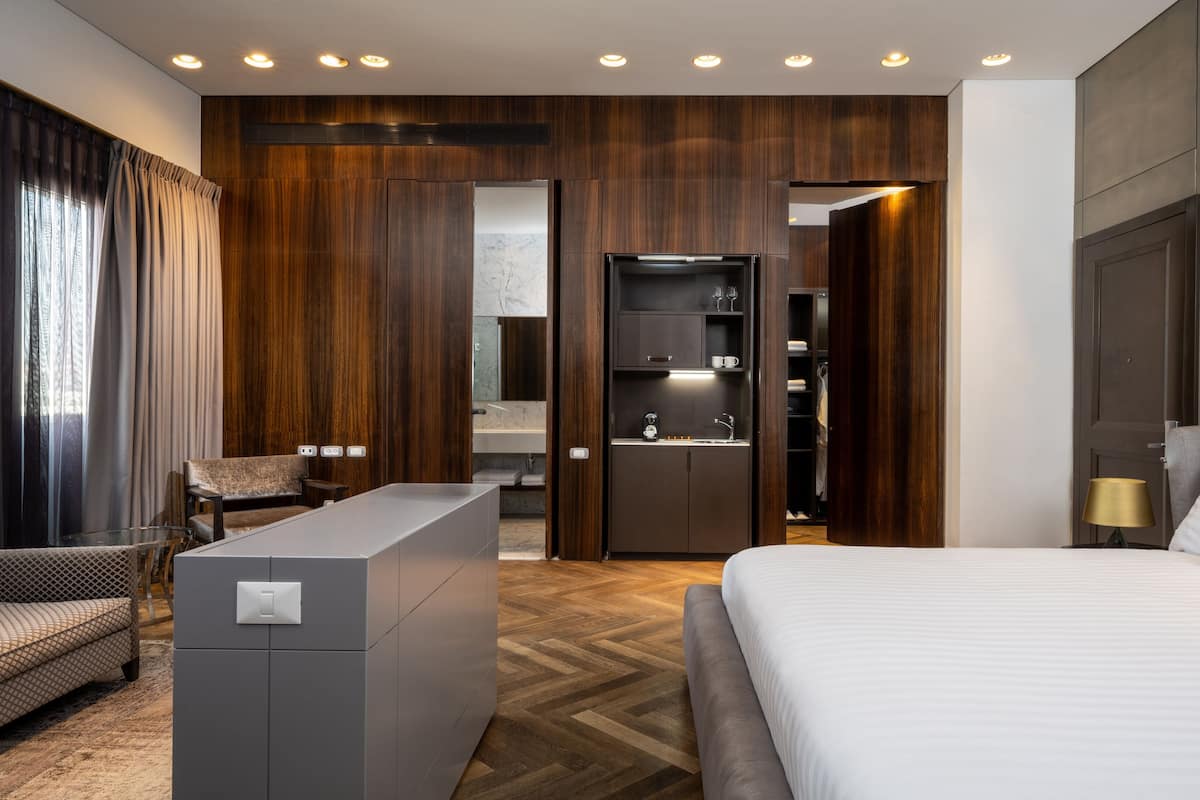 Een moderne hotelkamer met een bed, een zithoek, een kitchenette en een inloopkast.