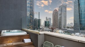 A balcony with a hot tub, wicker chairs, and a city view. - Hotel Indigo Tel Aviv - Diamond District by IHG (Ramat Gan)
