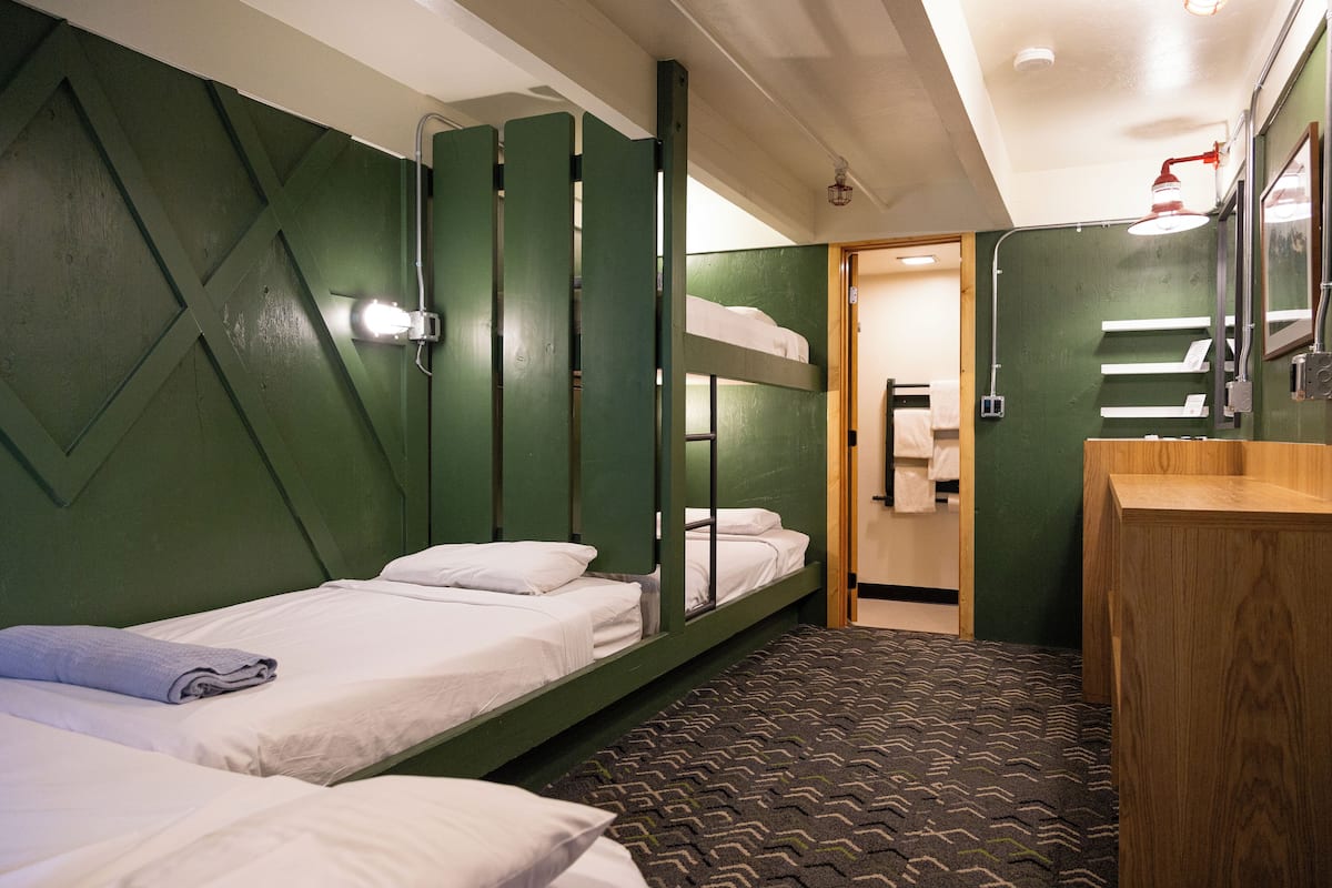 A small, compact room with bunk beds, a wooden desk, and a mirror.