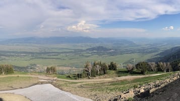Eine gebirgige Landschaft mit einem Tal, einem Fluss und einem fernen Bergmassiv.