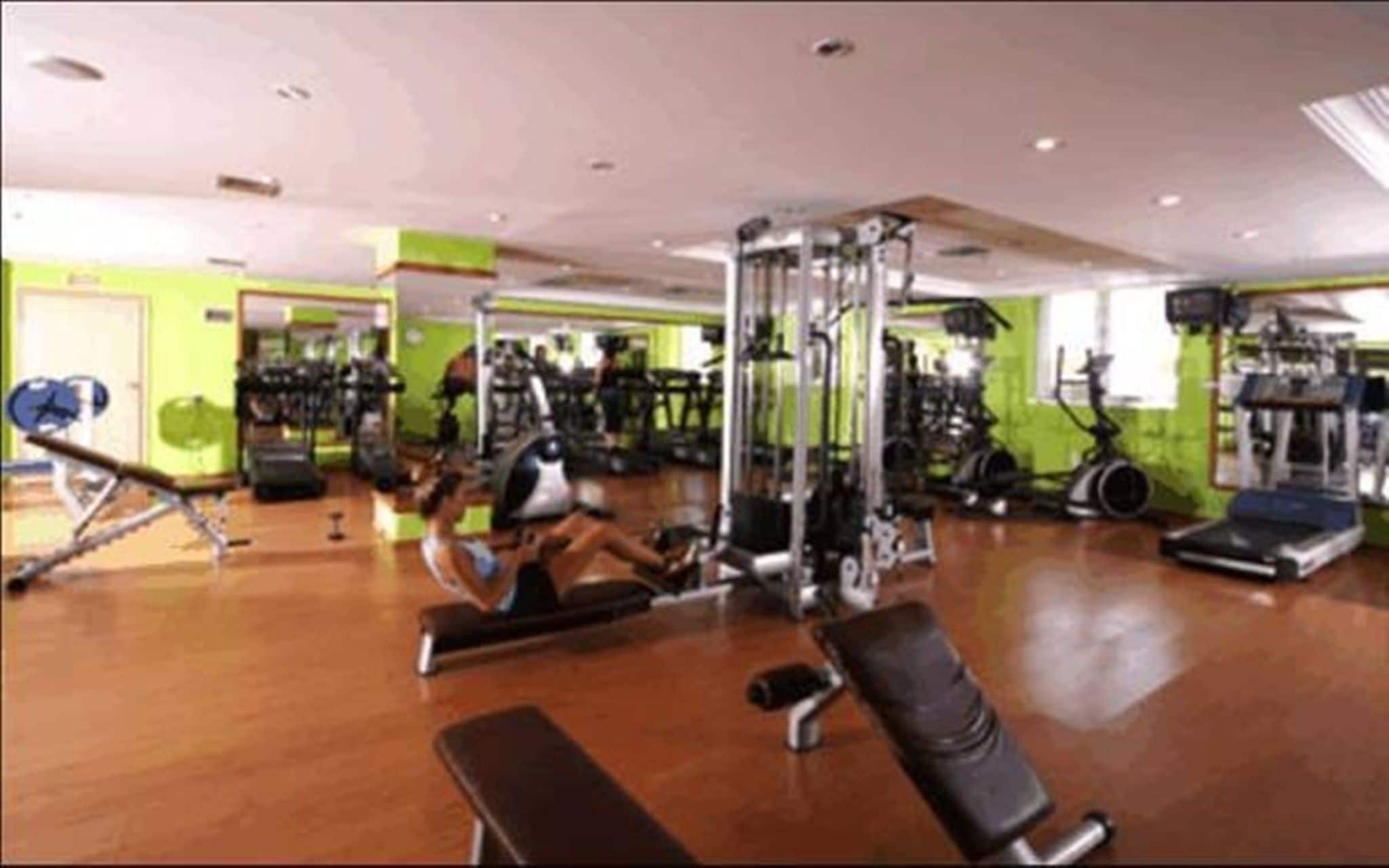 Un gimnasio con diversos equipos de ejercicio, incluyendo cintas de correr y máquinas de pesas.
