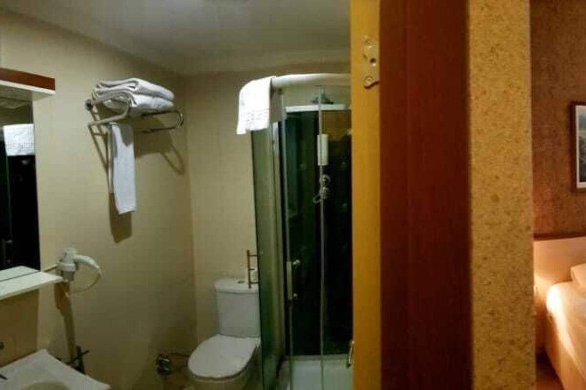 A hotel room with a bed, a bathroom, a television, and a clock on the wall.
