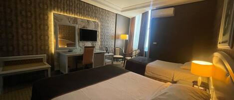 Una habitación de hotel con una cama grande, un escritorio con una silla, un televisor y una ventana con cortinas.