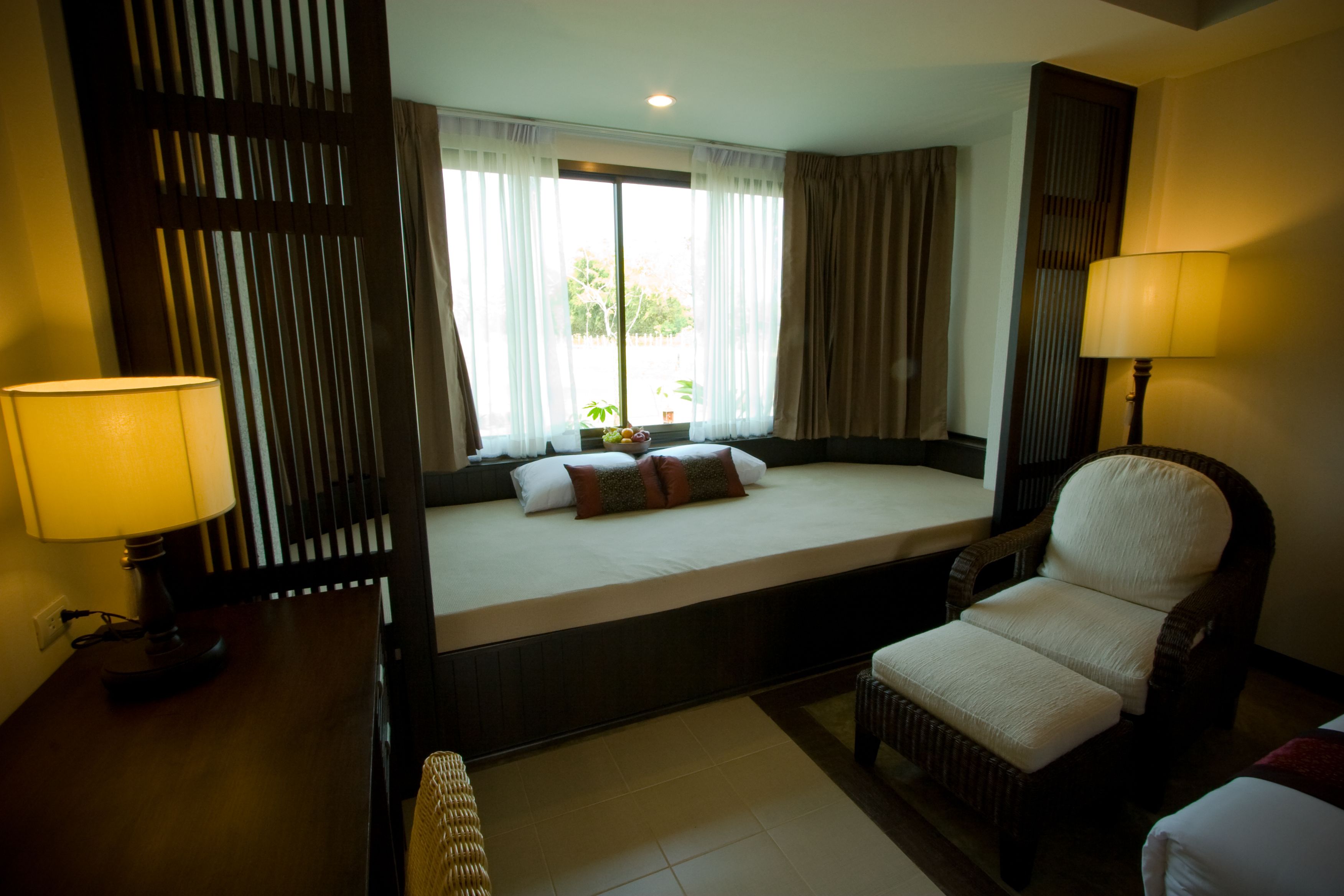 Una habitación de hotel con cama, una silla, un escritorio y una lámpara.