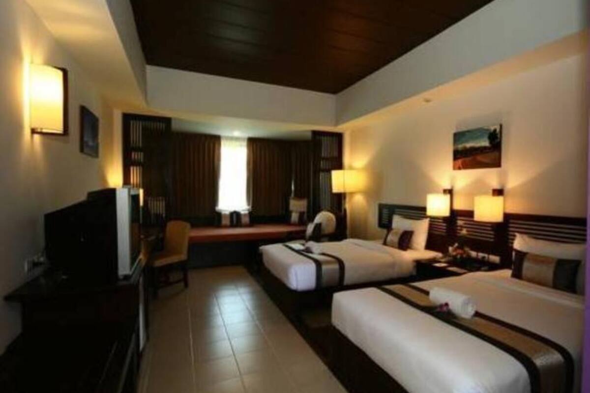 A hotel room with two beds, a desk, a chair, and a television.