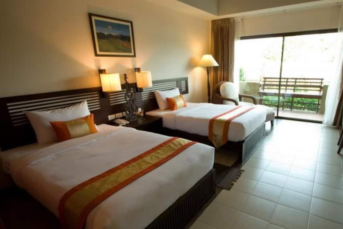 A hotel room with two beds, a large window, and a view of a balcony.