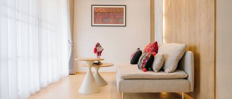 A modern living room with a sofa, a small round table, and a wall-mounted air conditioner.