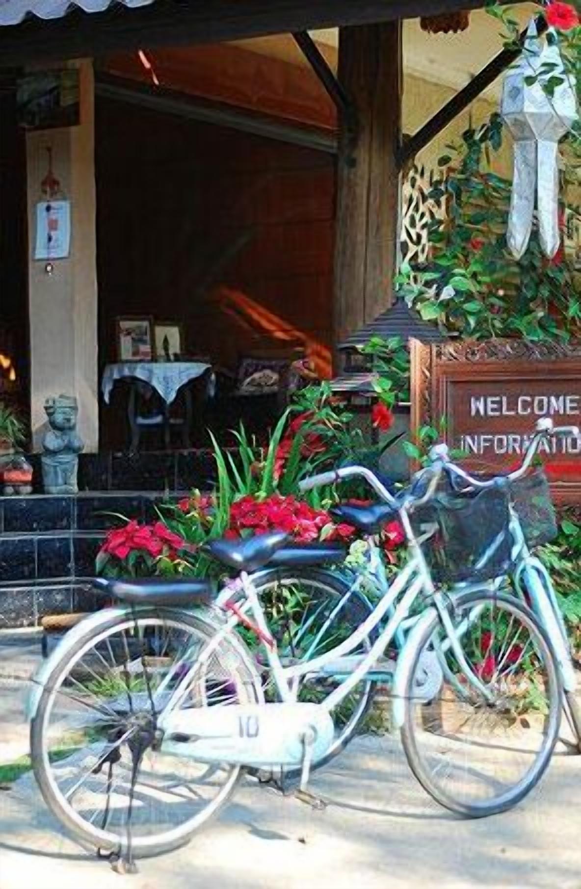 A bicycle parked in front of a building with a 'Welcome Information' sign.