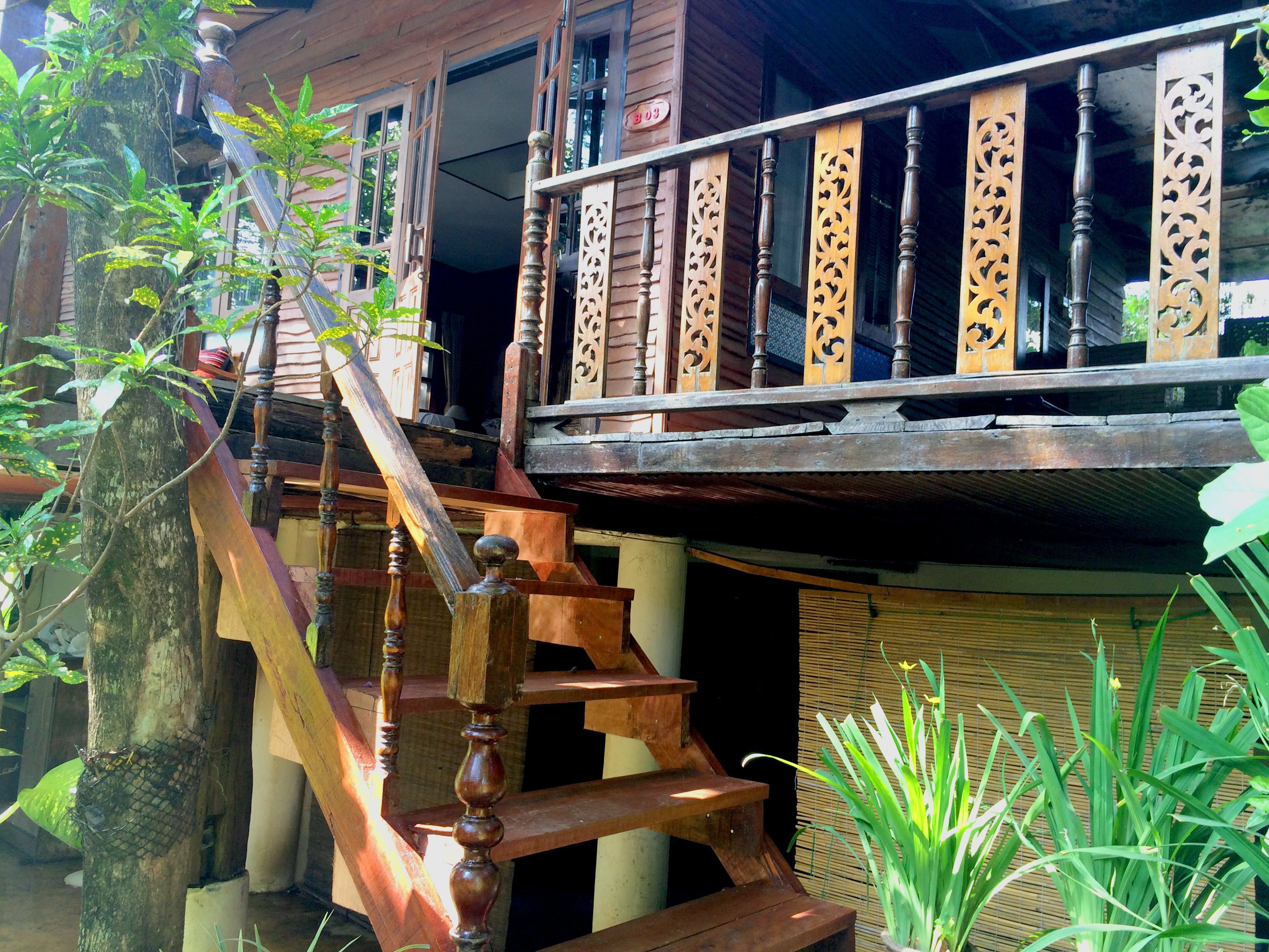 A wooden staircase with intricate balusters leading to a balcony with a decorative railing.