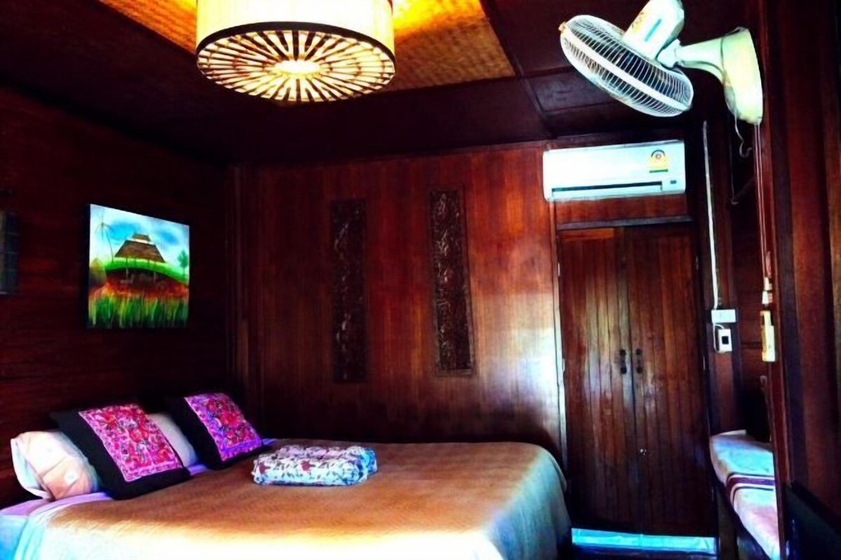 Une chambre équipée d’un lit, d’un ventilateur de plafond, d’un climatiseur et d’un téléviseur fixé au mur.