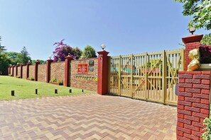 A gated entrance with a brick wall and a metal gate.