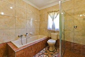 A bathroom with a bathtub, toilet, and glass shower enclosure.