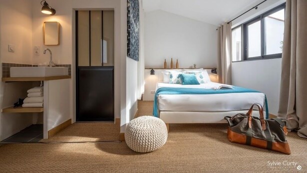 A modern bedroom with a bed, bedside table, and a large window. - Accostage Hotel (La Rochelle)