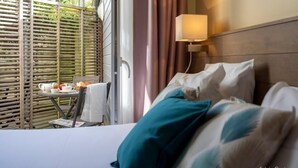 A hotel room with a bed, a table with a teapot and cups, and a view of a balcony with a wooden fence. - Accostage Hotel (La Rochelle)
