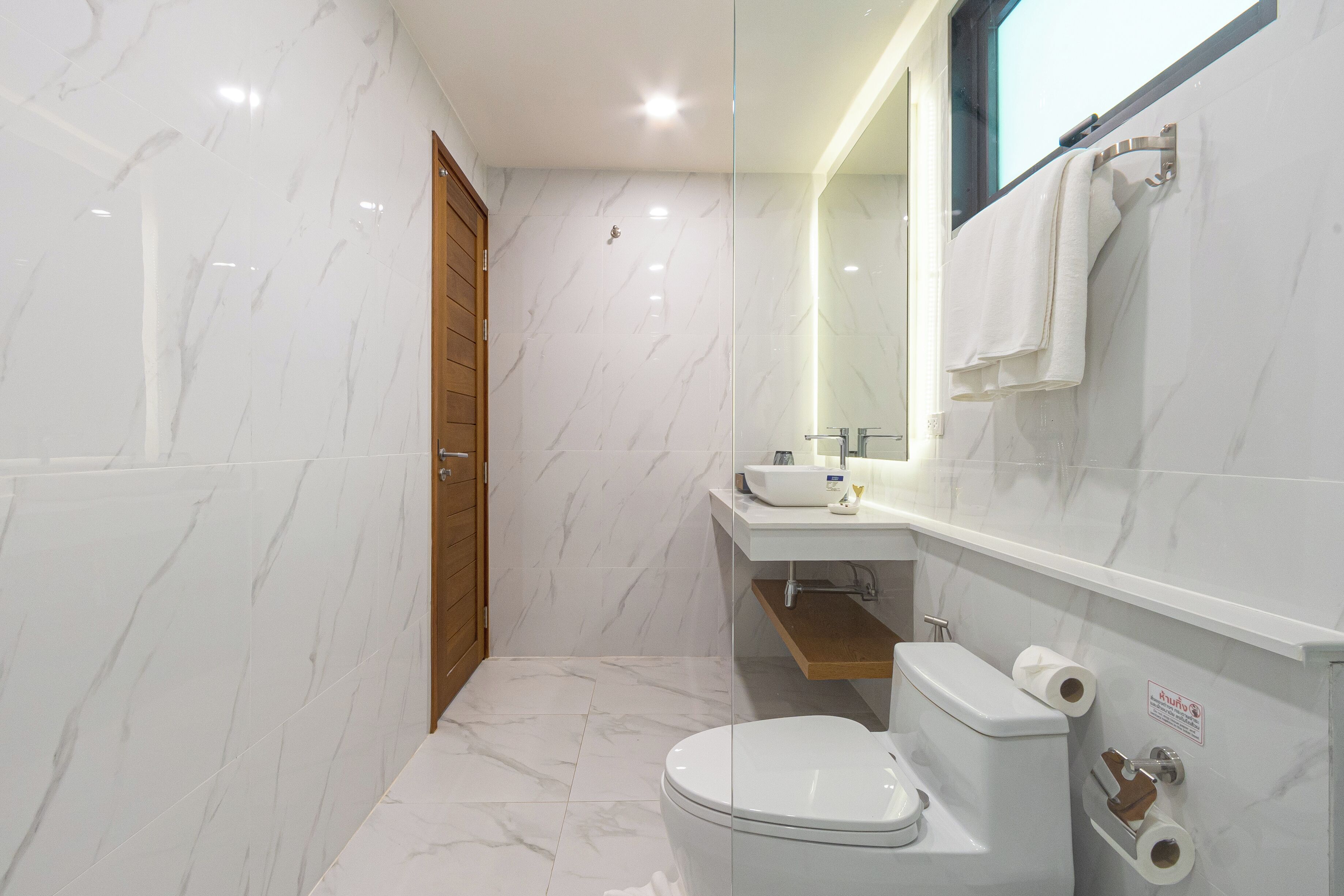 A modern bathroom with a toilet, sink, and mirror.