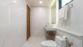 Een moderne badkamer met toilet, wastafel en spiegel.