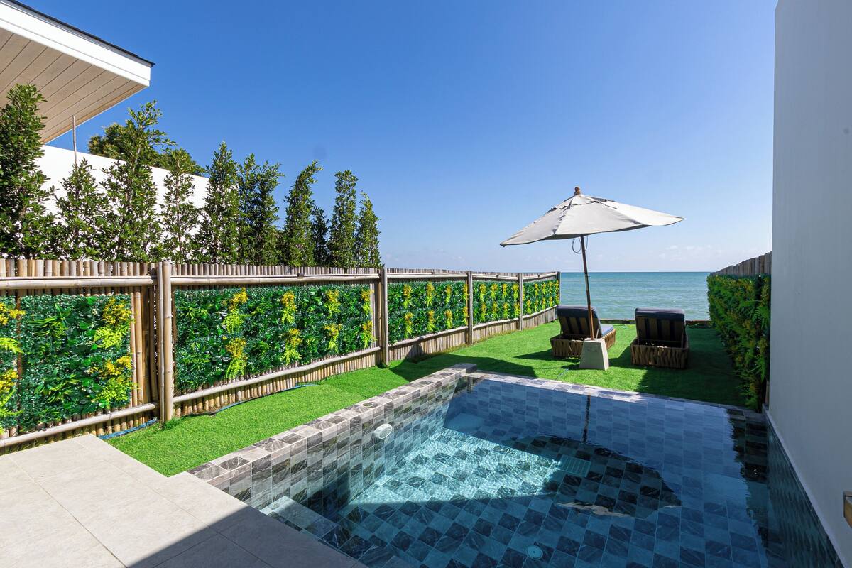 Piscina com borda azulejada, rodeada por um cercado de madeira e vegetação exuberante.