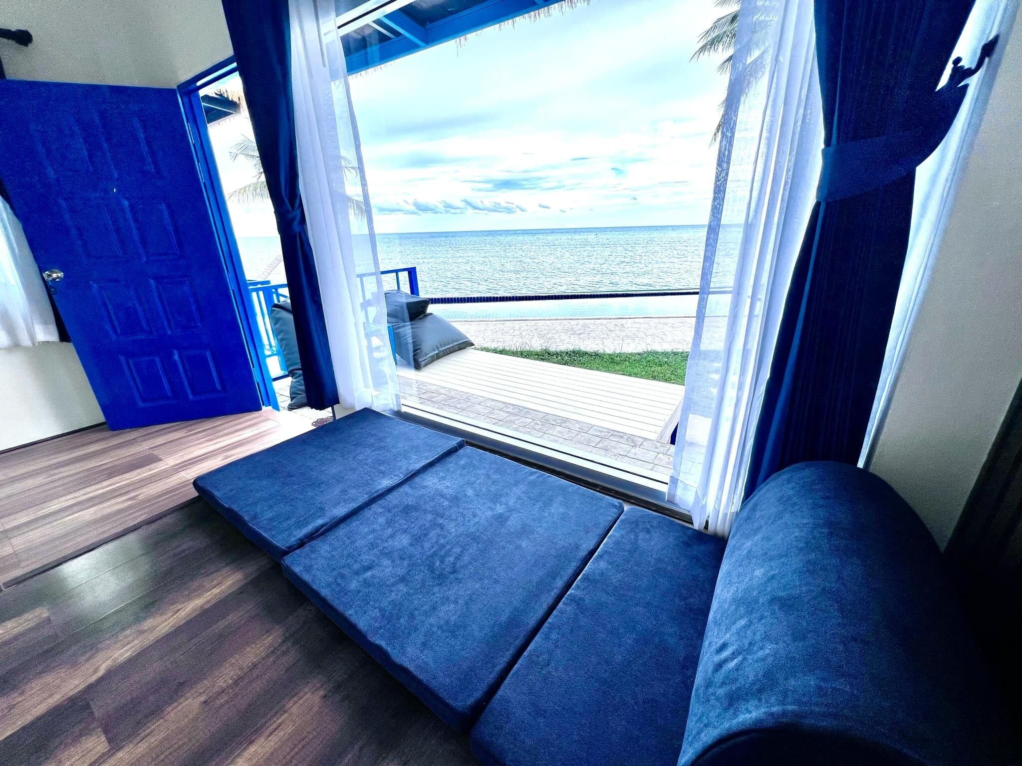 Una habitación con vista al mar, una puerta azul y suelo de madera.