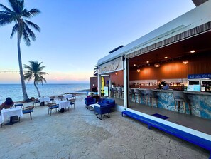 An outdoor bar area with a view of the ocean, tables and chairs, and a sign for Whale Cafe. - Three Trees Samui Resort - Sarocha Villa (Koh Samui)