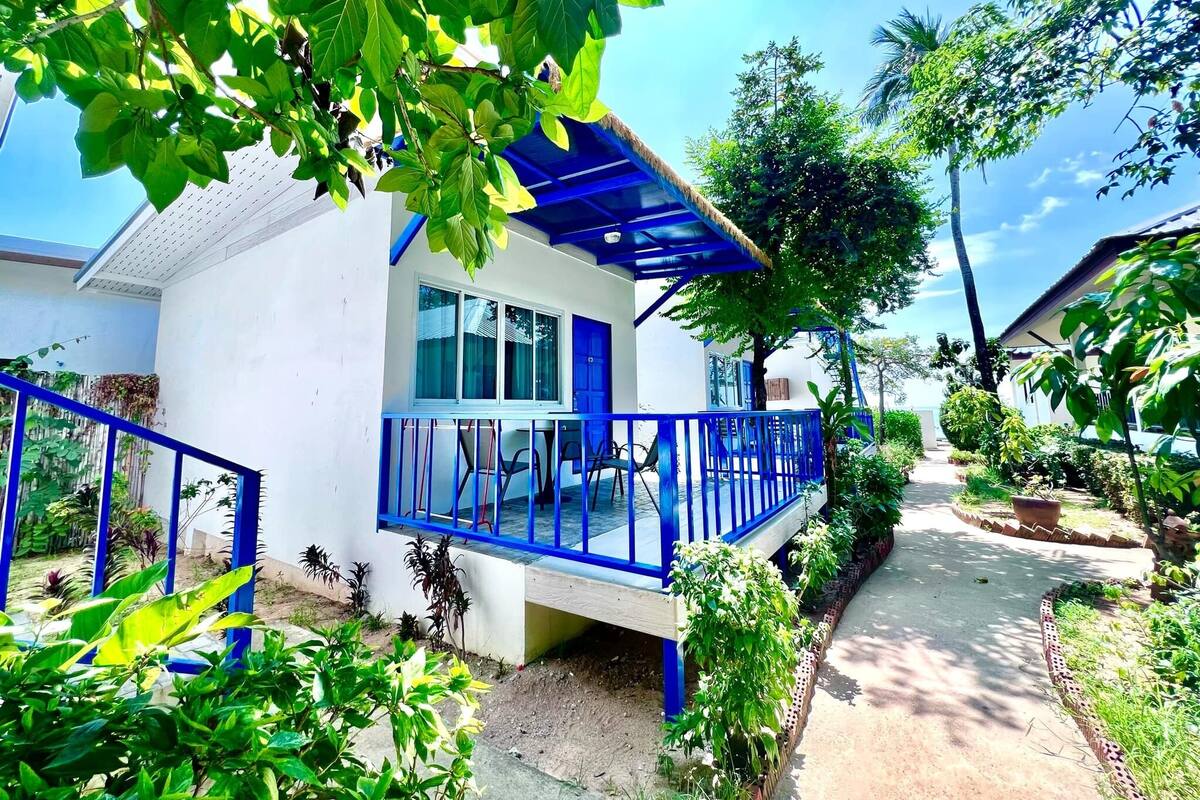 Um edifício branco com varanda azul e telhado de palha.