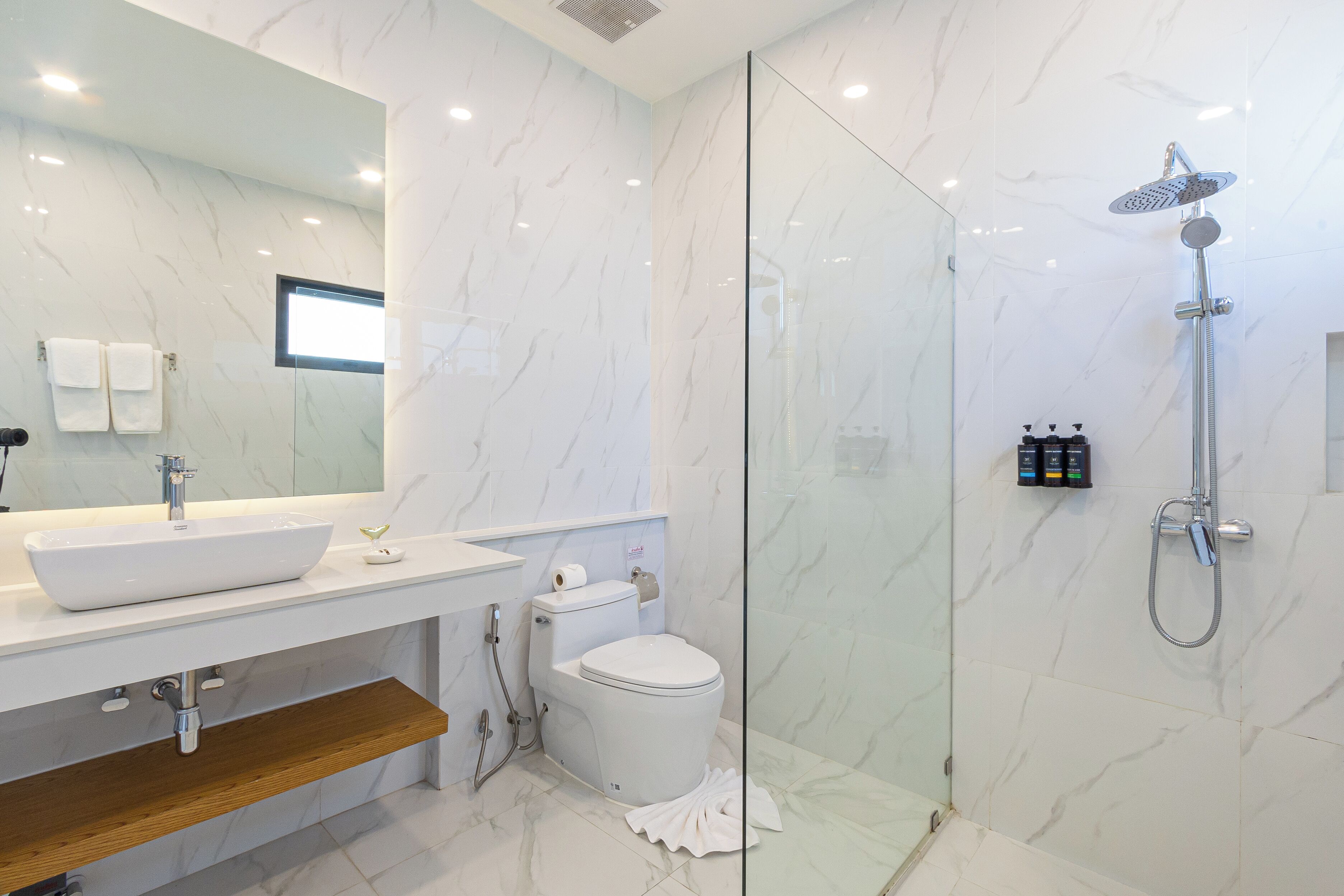 A modern bathroom with a glass-enclosed shower, a white sink, and a toilet.