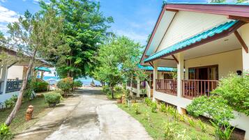 A pathway leading to a building with a porch and a view of the sea.