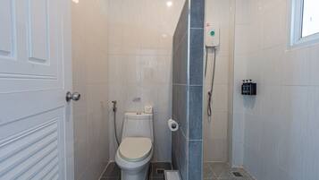Ein Badezimmer mit Toilette, Dusche und einem Handtrockner.