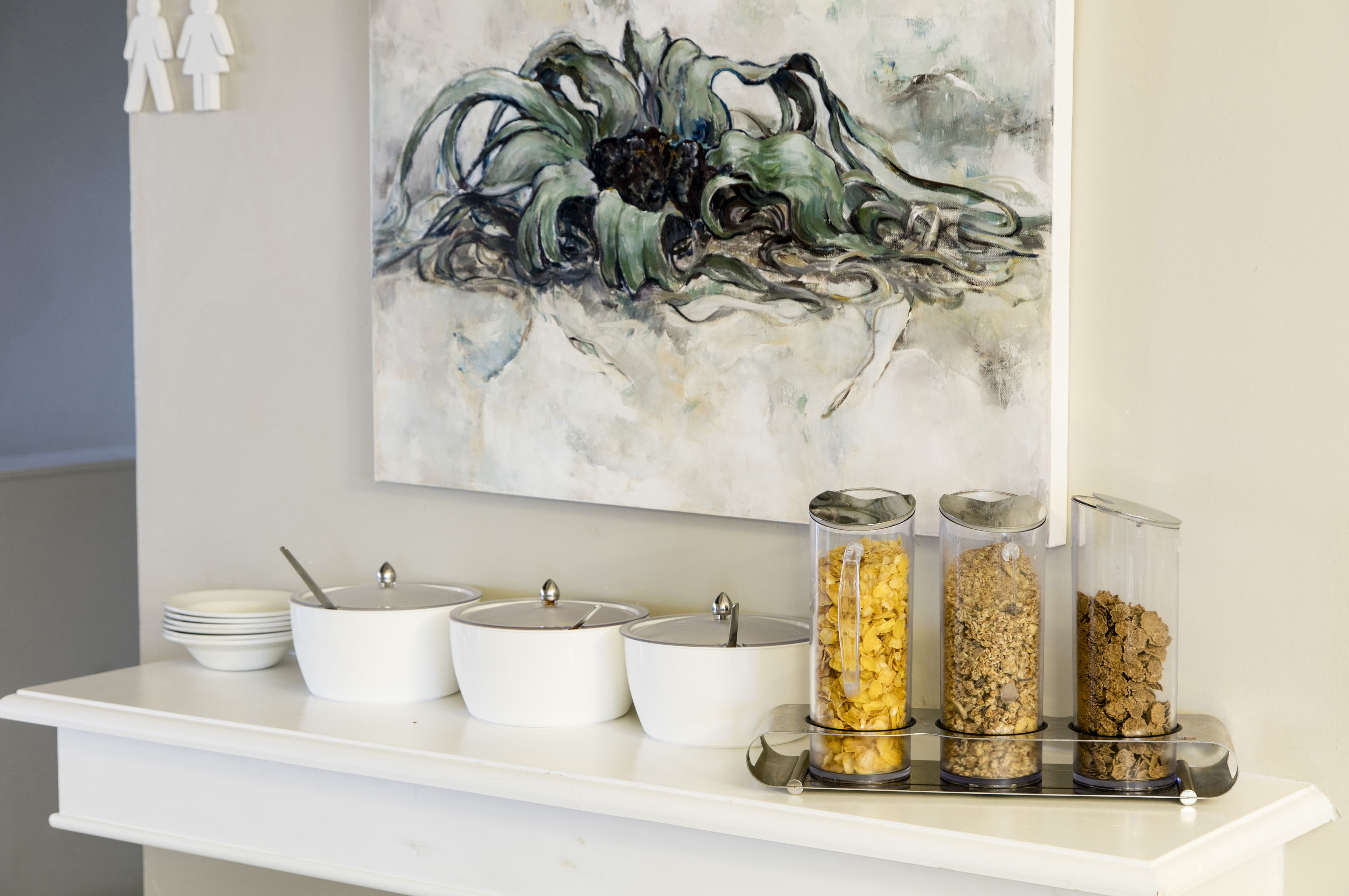 A breakfast bar with white bowls and containers of granola.