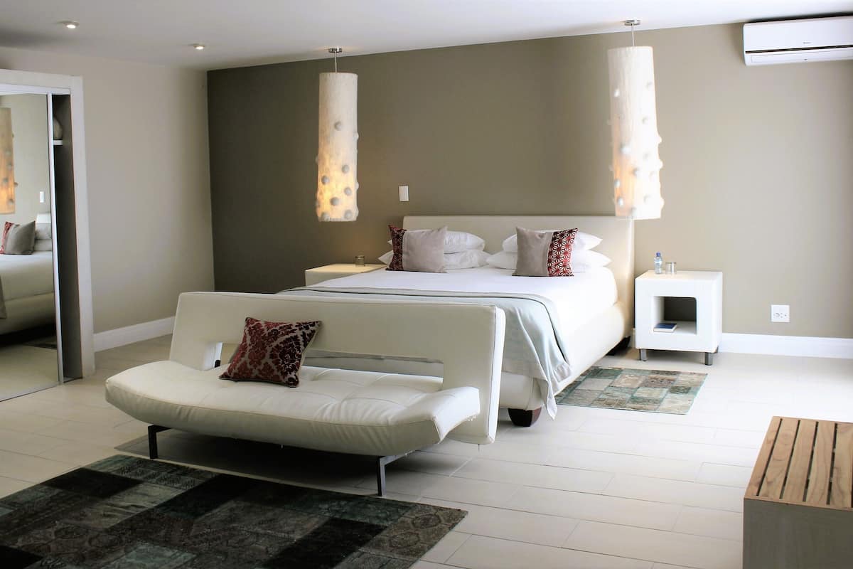 A modern bedroom with a bed, a sofa, a nightstand, and a wooden side table.