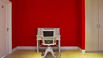 Une pièce avec un mur rouge, un bureau blanc avec des tiroirs et une porte blanche portant le numéro 39.