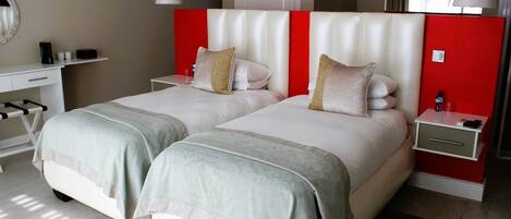 A hotel room with two beds, a desk, and a nightstand.