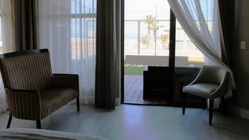 A hotel room with a large sliding glass door leading to an outdoor deck. Inside, there is a striped armchair and a plain chair.
