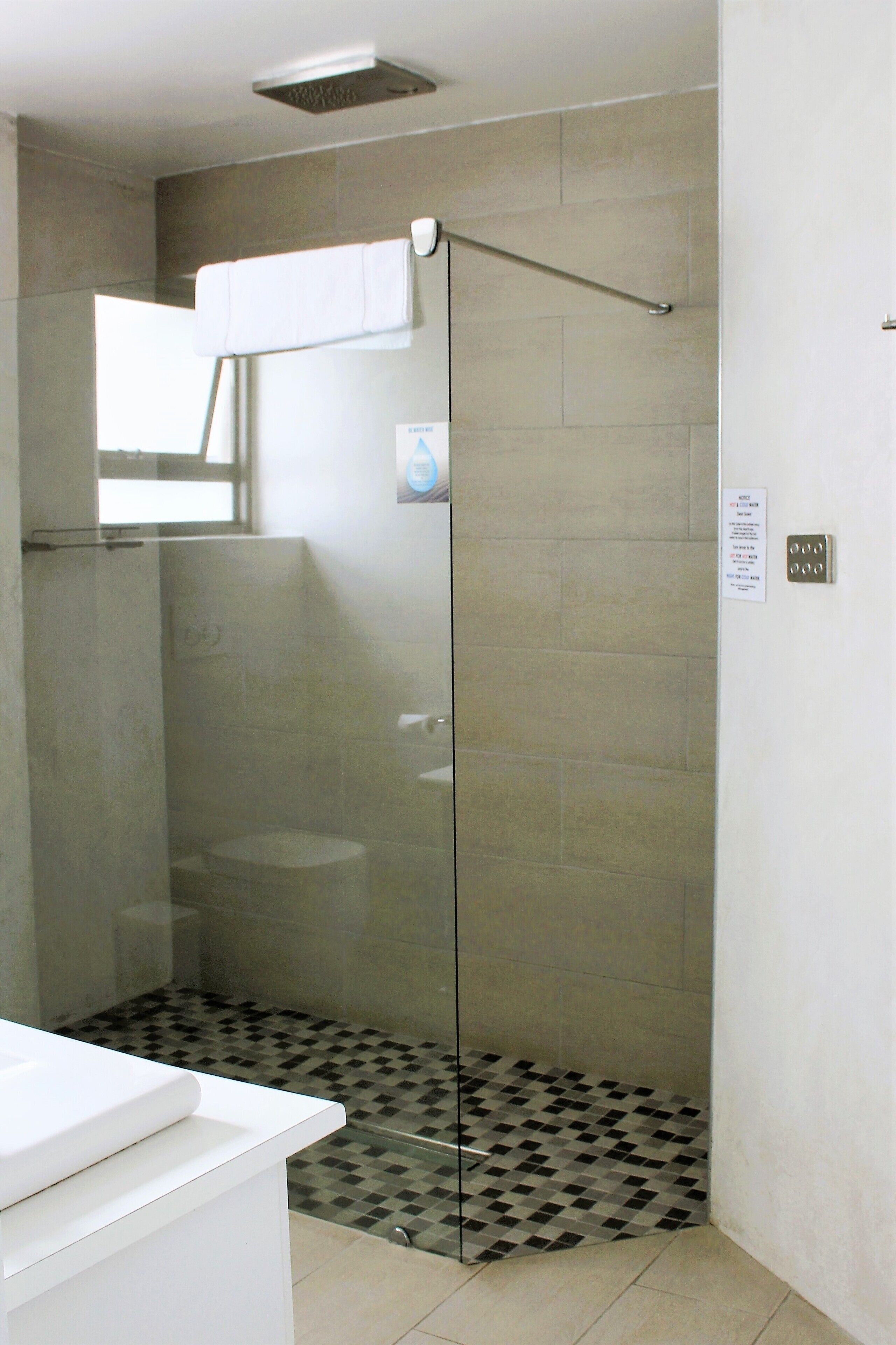 Une salle de bain moderne avec une douche à parois de verre, un lavabo blanc et un sol carrelé.