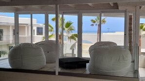 A room with large windows, a view of the beach, and two bean bags. - Atlantic Villa Boutique Guesthouse (Swakopmund)