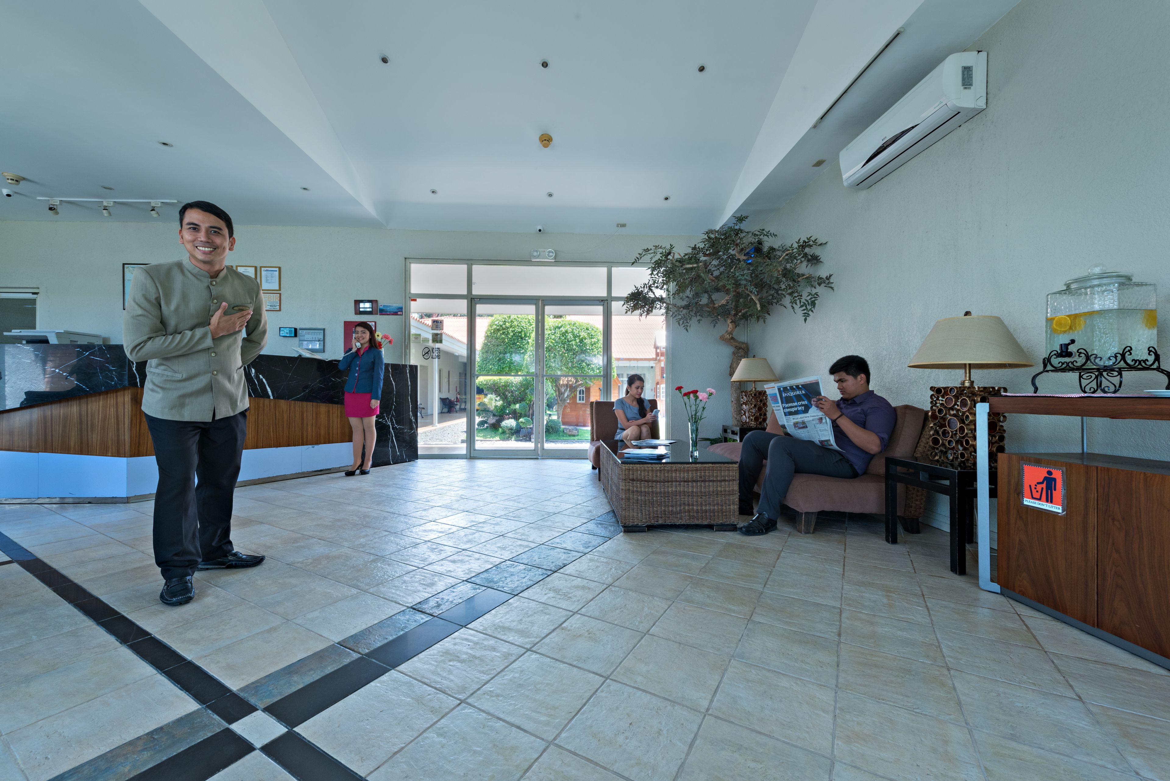 A hotel reception area with a reception desk, seating area, and a large window.