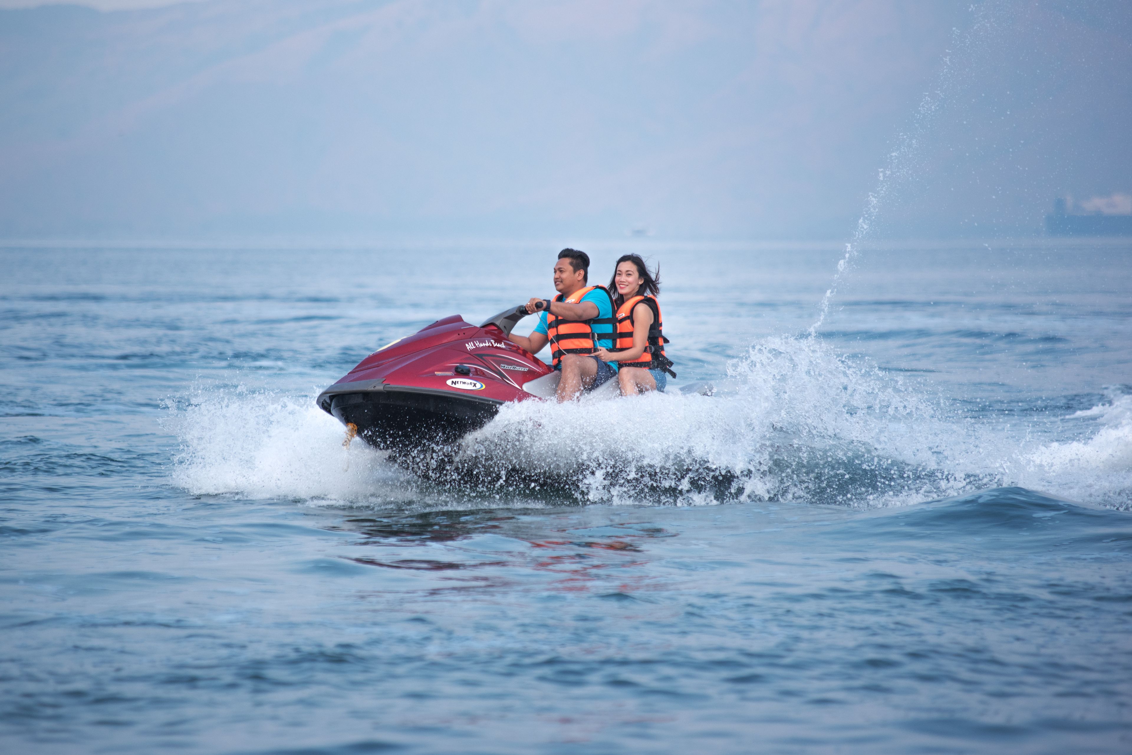 Two people on a jet ski with water splashing around them.