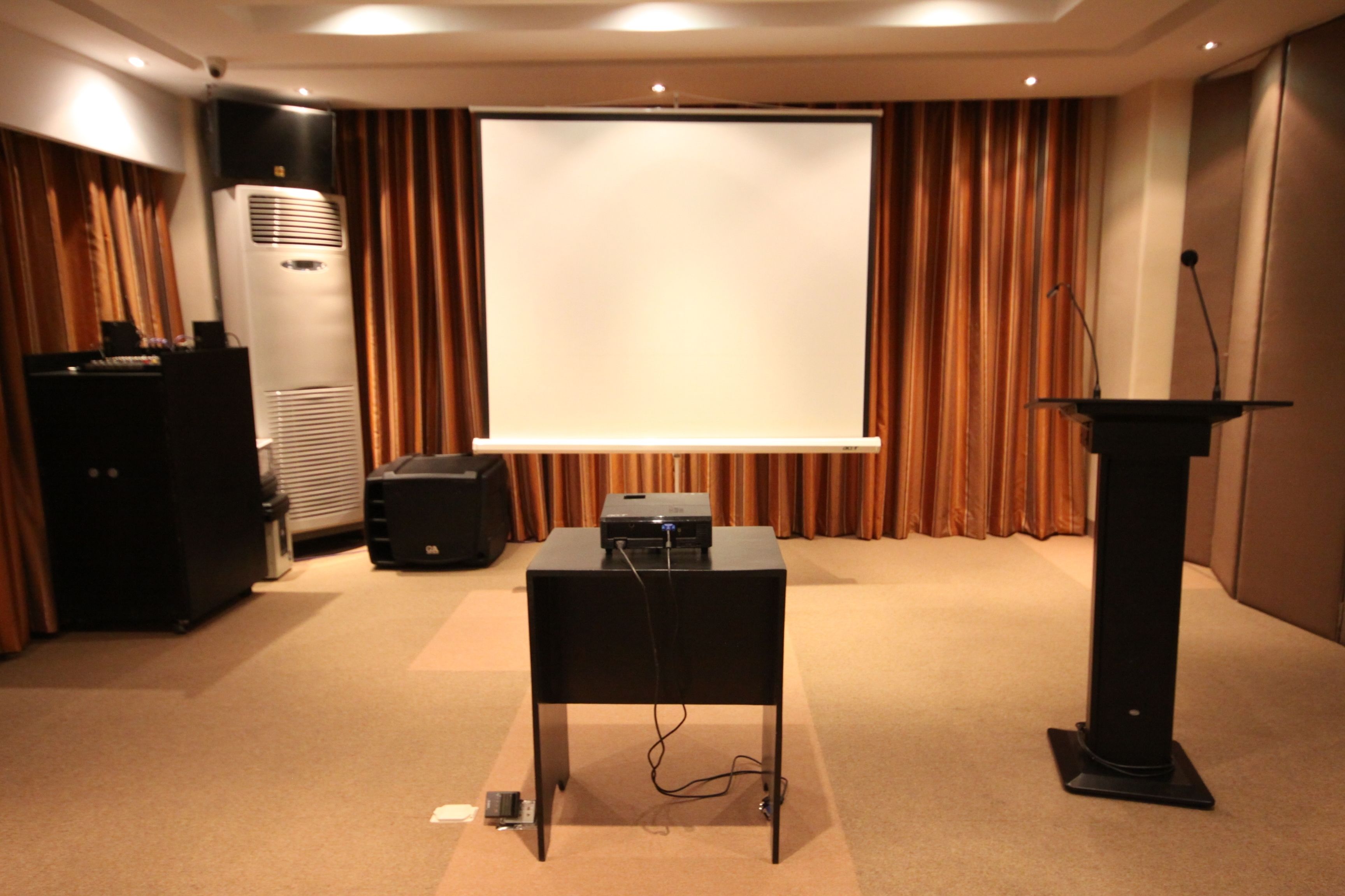 Une salle de conférence équipée d’un pupitre, d’un projecteur et d’un écran.
