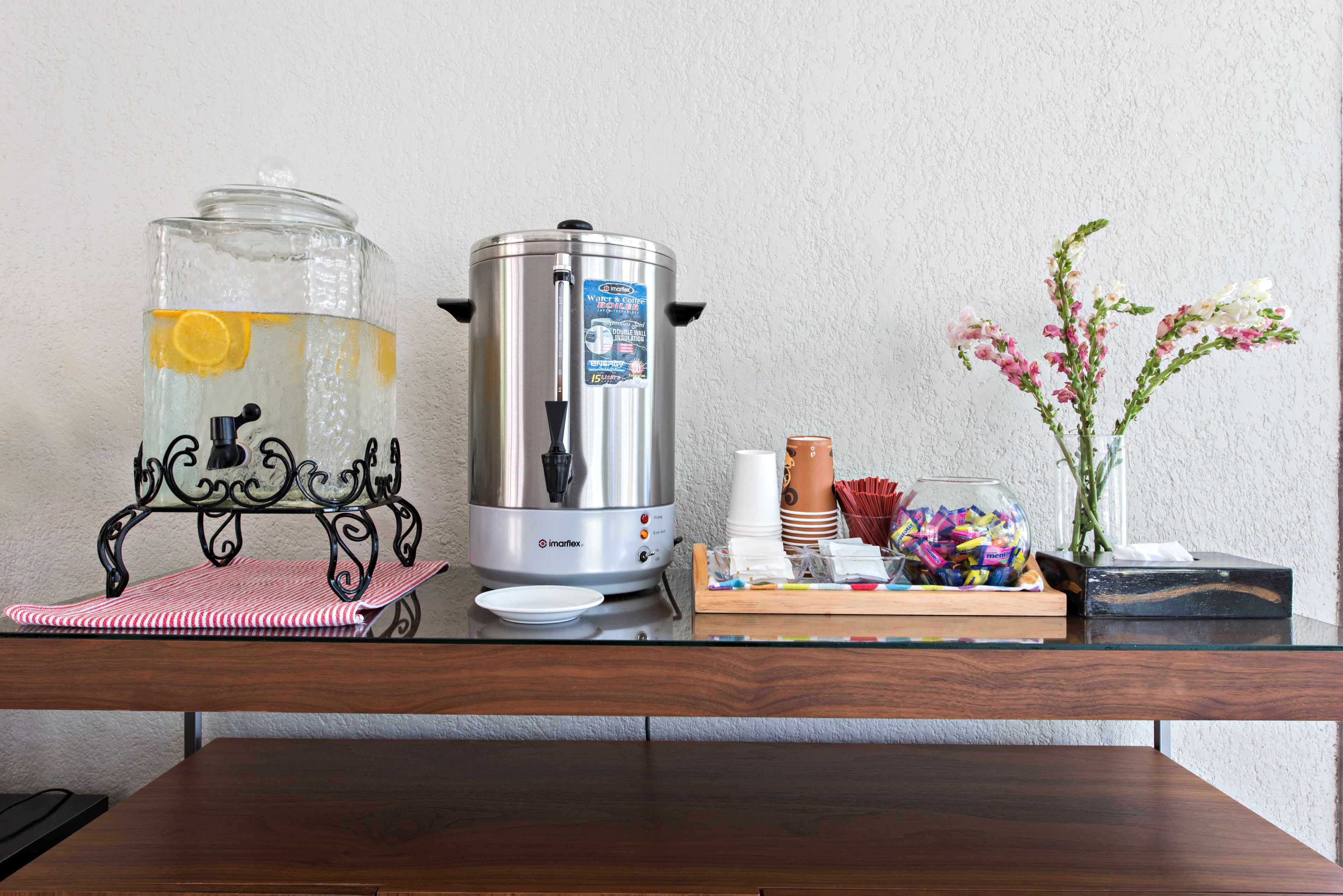 A kitchen counter with a coffee maker, a water dispenser, and a vase with flowers.