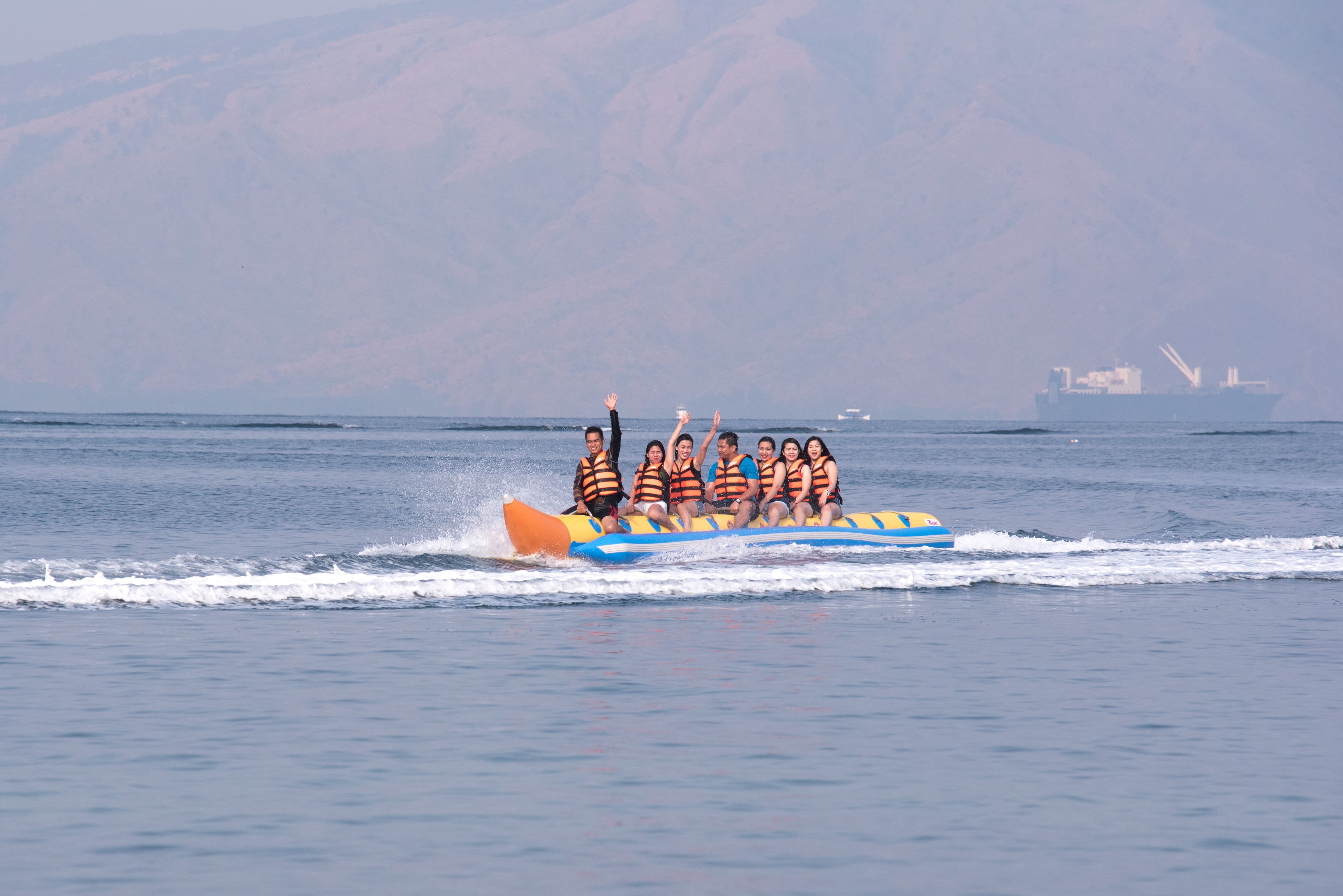 A group of people on a watercraft with a mountainous backdrop.