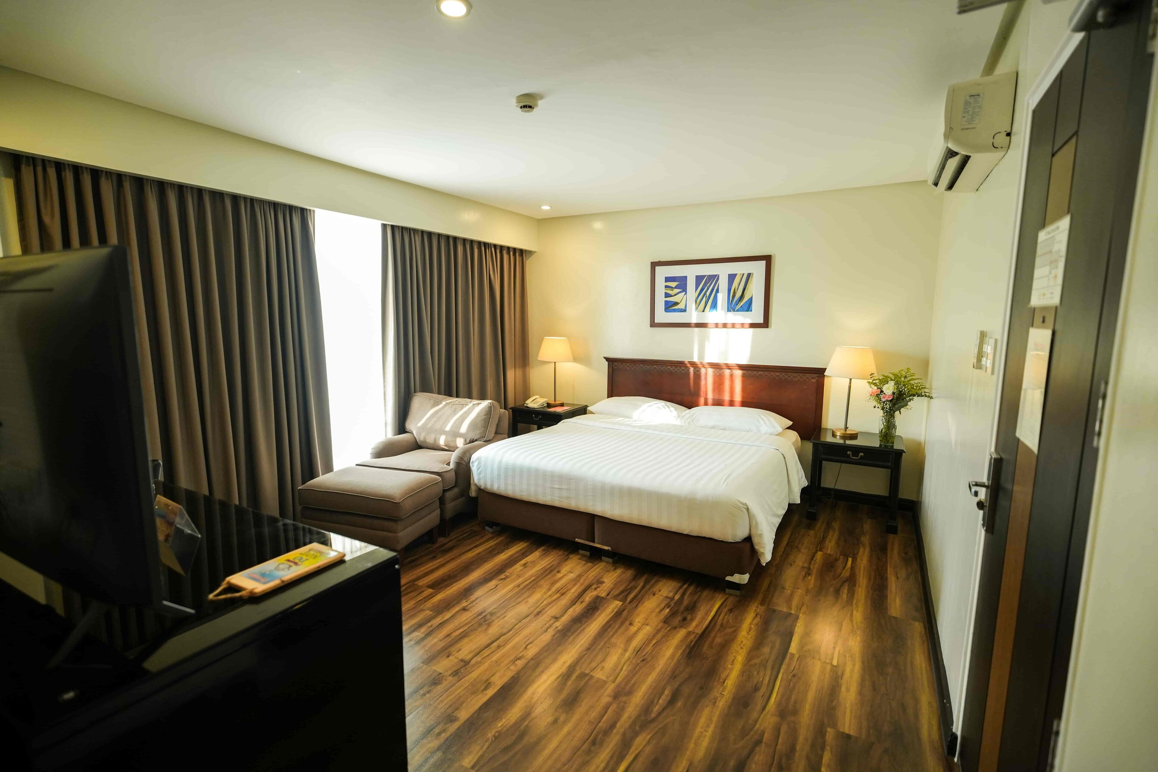 Una habitación de hotel con cama, televisor, escritorio y silla.