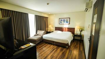 Una habitación de hotel con cama, televisor, escritorio y silla.