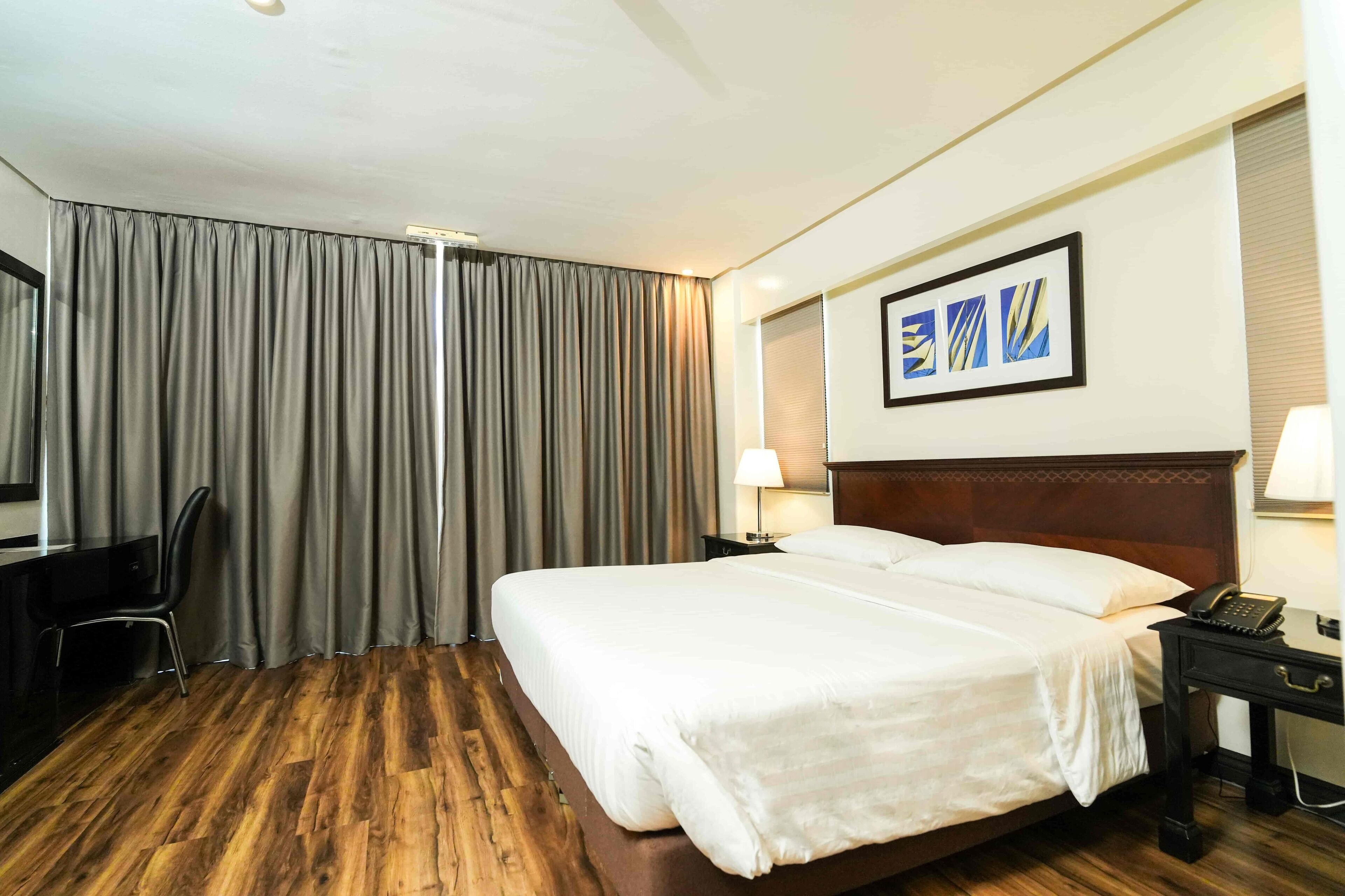 Une chambre d’hôtel avec un grand lit, un bureau avec une chaise, une lampe et un téléphone.