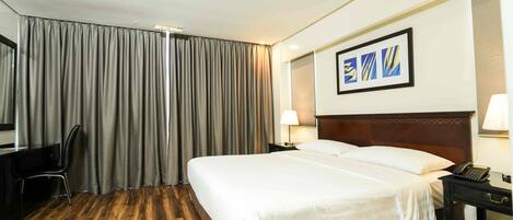 Une chambre d’hôtel avec un grand lit, un bureau avec une chaise, une lampe et un téléphone.