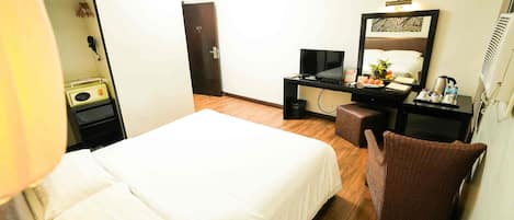 A hotel room with a bed, a desk with a computer, a chair, and a mirror.