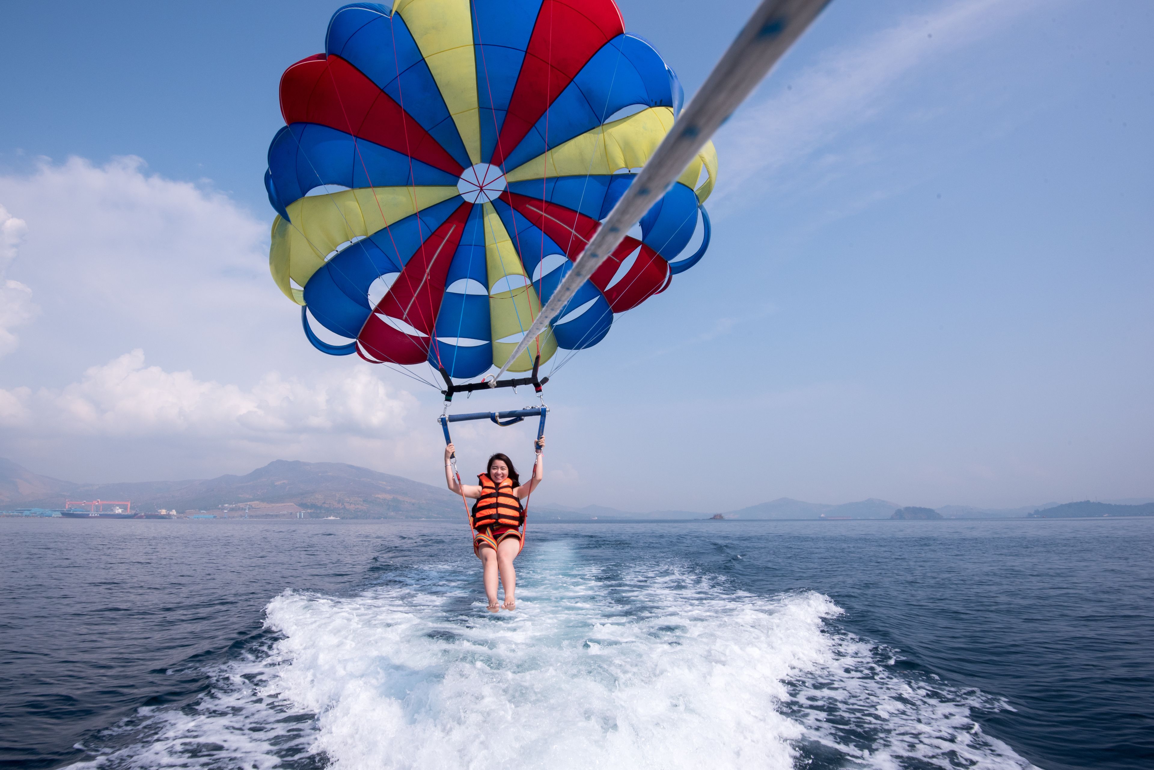 A person parasailing over water with a colorful parachute.