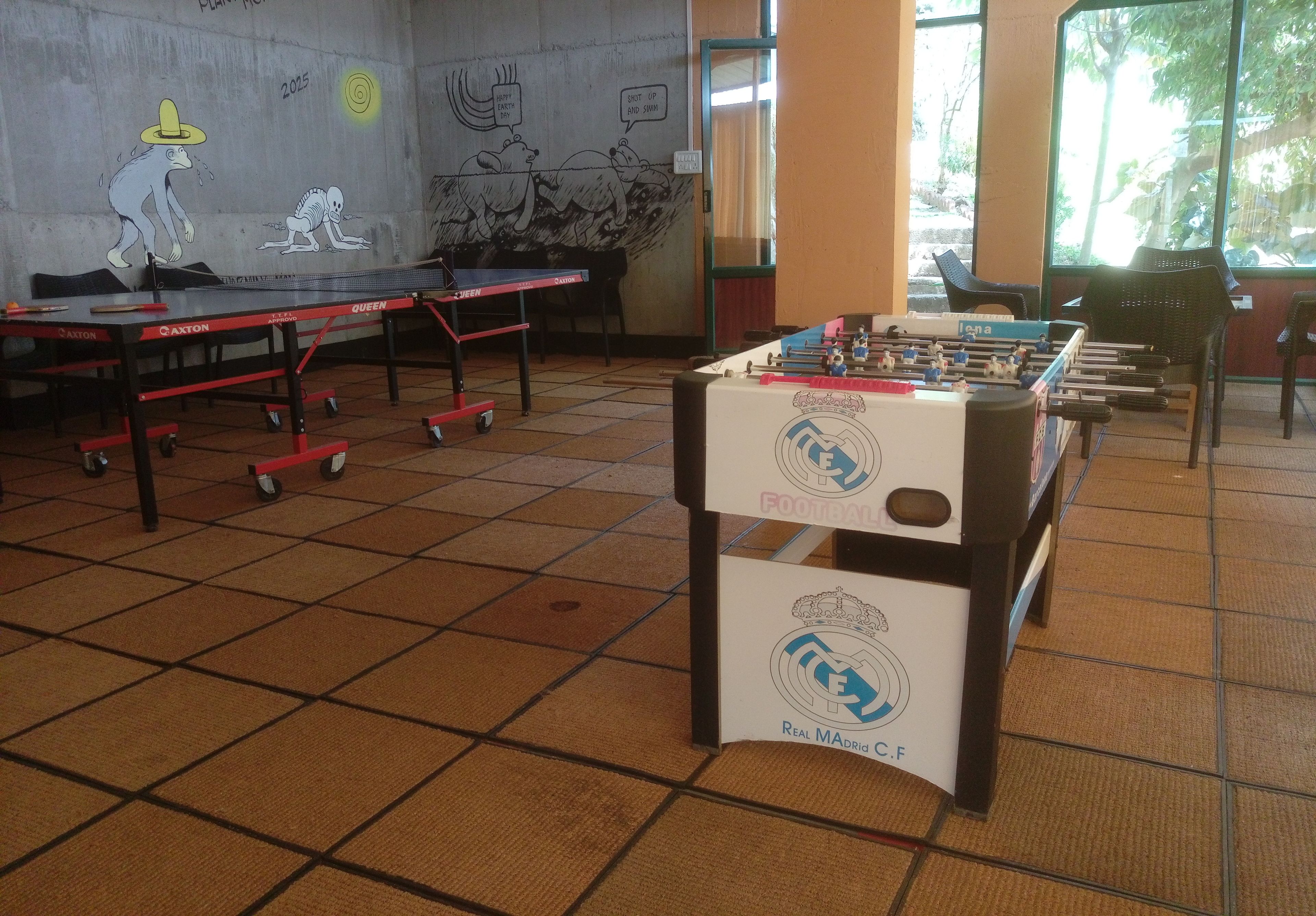 A room with a foosball table, ping pong table, and a table tennis table.